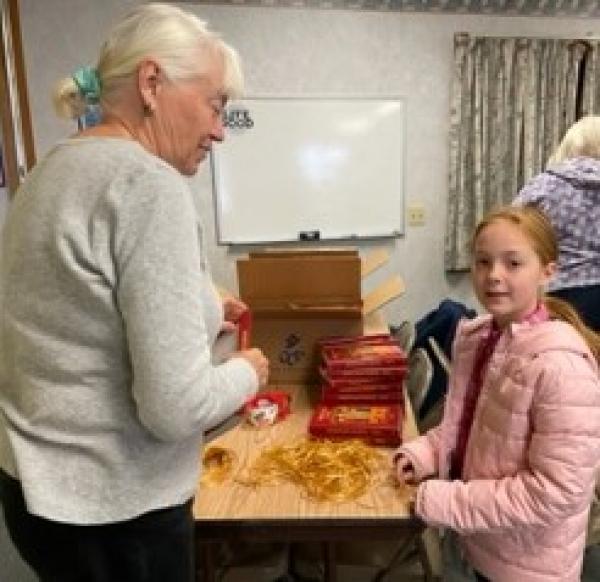 Financial Secretary Josh Lussier is assisted by her granddaughter as they work on putting ribbons in the missals.